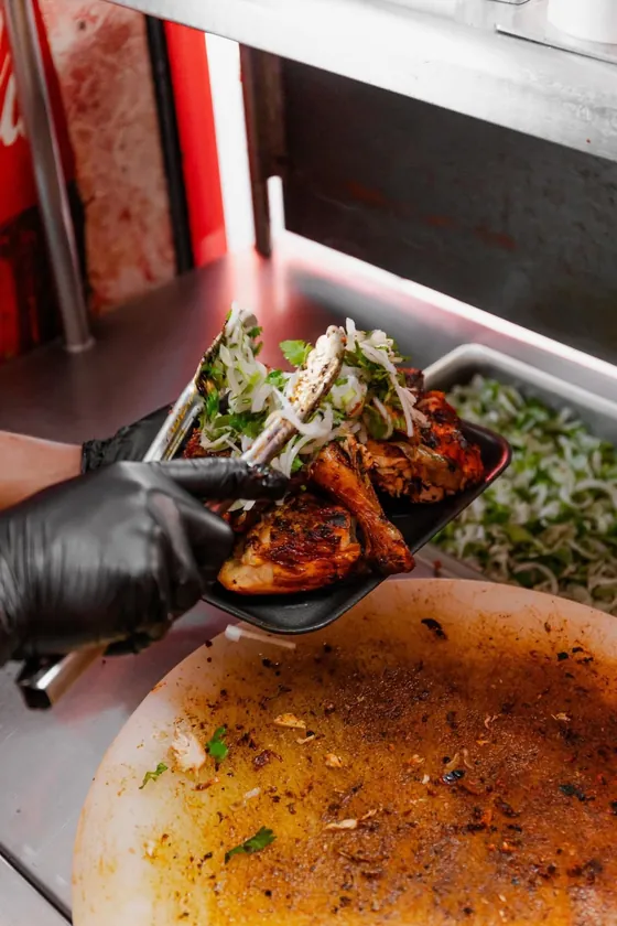 Parrillero sirviendo pollo asado con cebolla y cilantro